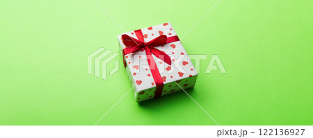 Valentine or other holiday handmade present in paper with red hearts and gifts box in holiday wrapper. Present box of gift on green colored table top view with copy space, empty space for design 122136927