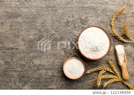 Flat lay of Wheat flour in wooden bowl with wheat spikelets on colored background. world wheat crisis 122136930