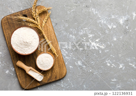 Flat lay of Wheat flour in wooden bowl with wheat spikelets on colored background. world wheat crisis 122136931