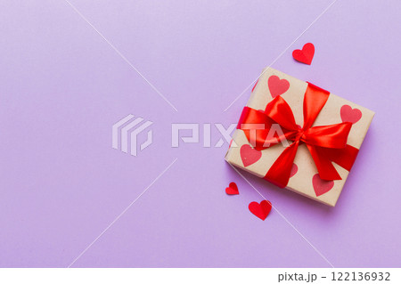 Top view photo of valentine day decorations gift box with red ribbon bow on colored background. Holiday gift boxes with top view 122136932