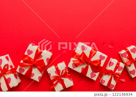 Top view photo of valentine day decorations gift box with red ribbon bow on colored background. Holiday gift boxes with top view 122136934