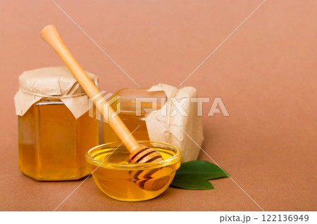 Honey in jar with leaves and honey dipper on colored background top view with copy text 122136949
