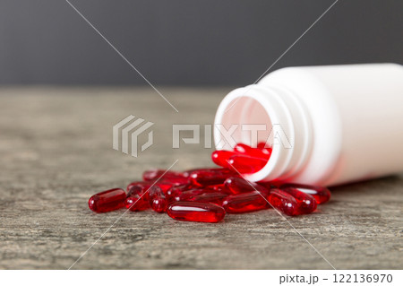 Red pills spilled around a pill bottle. Medicines and prescription pills flat lay background. Red medical capsules 122136970