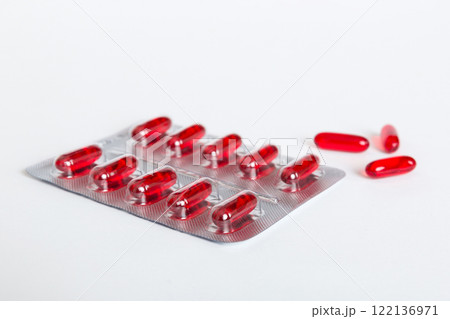 Blister package with Vitamin a on color background. Medicine pills on a light background. Medicines and prescription pills flat lay background. red medical tablets in blister Blister package with Vitamin a on color background. Medicine pills on a light background. Medicines and prescription pills flat lay background. red medical tablets in blister 122136971