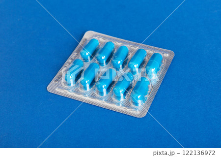 Blister package with Vitamin on color background. Medicine pills on a light background. Medicines and prescription pills flat lay background. blue medical tablets in blister Blister package with Vitamin on color background. Medicine pills on a light background. Medicines and prescription pills flat lay background. blue medical tablets in blister 122136972