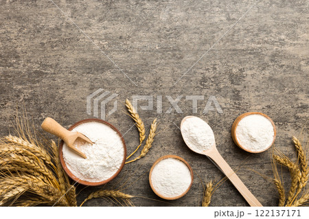 Flat lay of Wheat flour in wooden bowl with wheat spikelets on colored background. world wheat crisis Flat lay of Wheat flour in wooden bowl with wheat spikelets on colored background. world wheat crisis 122137171