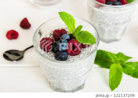 Healthy breakfast or morning with chia seeds vanilla pudding raspberry and blueberry berries on table background, vegetarian food, diet and health concept. Chia pudding with raspberry and blueberry Healthy breakfast or morning with chia seeds vanilla pudding raspberry and blueberry berries on table background, vegetarian food, diet and health concept. Chia pudding with raspberry and blueberry 122137209