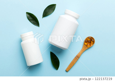 Omega-3 capsules lie in white bottle on a table with green leaves background. Fish oil tablets. Biologically active additives. omega 6, omega 9, vitamin A, E, D, vitamin D3 top view with copy space Omega-3 capsules lie in white bottle on a table with green leaves background. Fish oil tablets. Biologically active additives. omega 6, omega 9, vitamin A, E, D, vitamin D3 top view with copy space 122137219