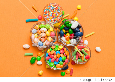 different colored round candy in bowl and jars. Top view of large variety sweets and candies with copy space 122137252