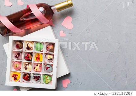 Bottle of red wine on colored background for Valentine Day with gift and chocolate. Heart shaped with gift box of chocolates top view with copy space Bottle of red wine on colored background for Valentine Day with gift and chocolate. Heart shaped with gift box of chocolates top view with copy space 122137297
