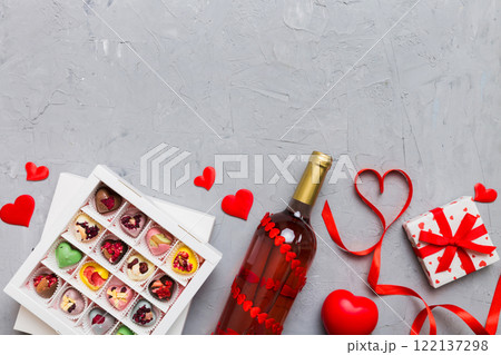 Bottle of red wine on colored background for Valentine Day with gift and chocolate. Heart shaped with gift box of chocolates top view with copy space Bottle of red wine on colored background for Valentine Day with gift and chocolate. Heart shaped with gift box of chocolates top view with copy space 122137298