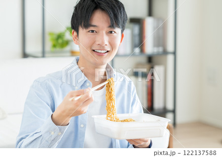 インスタントの焼きそばを食べる若い男性 122137588