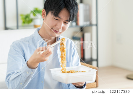 インスタントの焼きそばを食べる若い男性 122137589