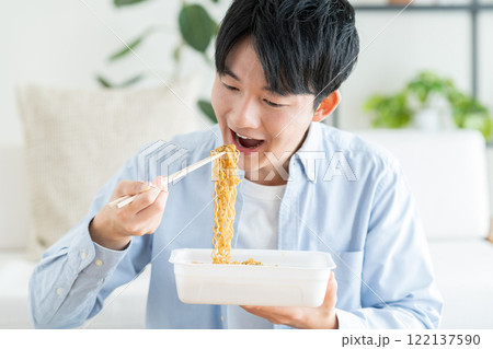 インスタントの焼きそばを食べる若い男性 122137590
