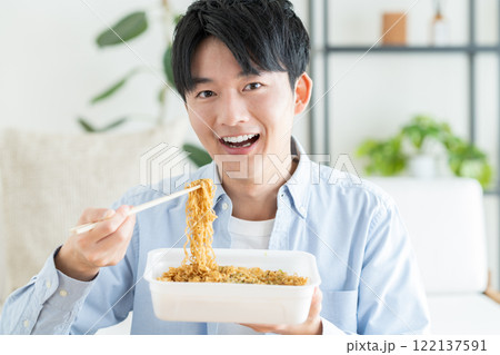 インスタントの焼きそばを食べる若い男性 122137591