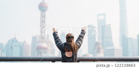 woman traveler visiting in Shanghai, China. Female Tourist with backpack sightseeing Shanghai view of Lujiazui in The Bund of Shanghai. landmark and popular for tourism attractions. Vacation concept 122138663