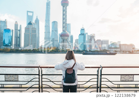 woman traveler visiting in Shanghai, China. Female Tourist with backpack sightseeing Shanghai view of Lujiazui in The Bund of Shanghai. landmark and popular for tourism attractions. Vacation concept 122138679