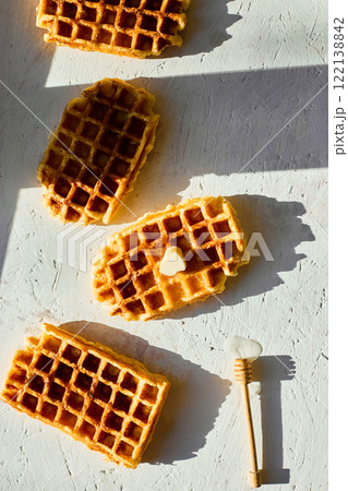 Delicious waffles topped with a touch of honey on a bright background in the morning light Delicious waffles topped with a touch of honey on a bright background in the morning light 122138842