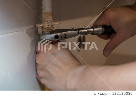 A Close-Up of a Hand Using a Wrench to Adjust a Plumbing Valve A Close-Up of a Hand Using a Wrench to Adjust a Plumbing Valve 122139050