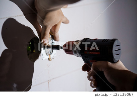 Close-up of a Hand Using a Power Drill for Electrical Installation in a Wall Close-up of a Hand Using a Power Drill for Electrical Installation in a Wall 122139067