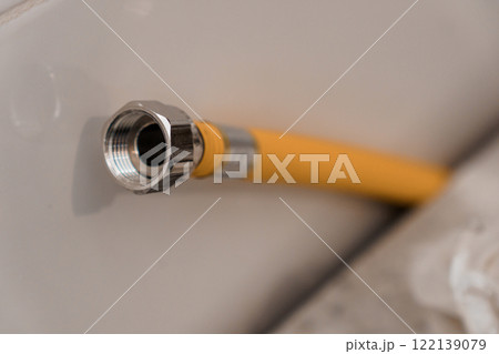 Close-Up of a Yellow Water Hose Connector against a White Surface Close-Up of a Yellow Water Hose Connector against a White Surface 122139079