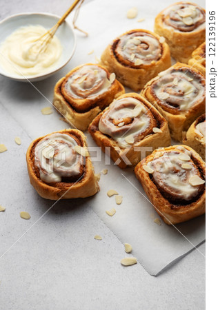 Freshly baked cinnamon rolls topped with cream cheese frosting and almond slivers Freshly baked cinnamon rolls topped with cream cheese frosting and almond slivers 122139196