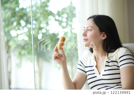 Asian woman holding doughnut looking through window 122139991