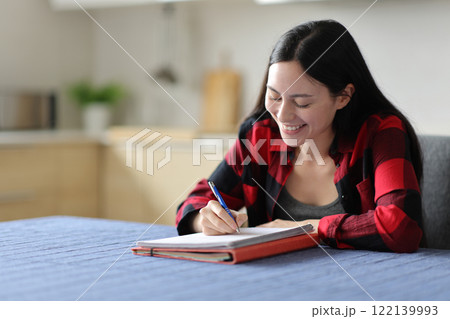 Happy asian student learning taking notes in the kitchen 122139993