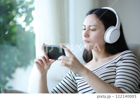 Serious asian woman watching media on phone Serious asian woman watching media on phone 122140005