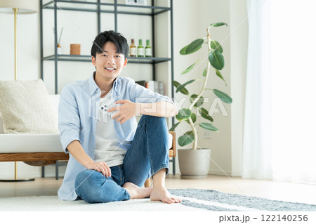 リビングでスマホを見る若い男性 122140256