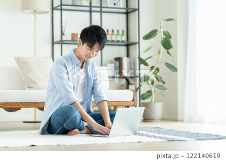 リビングでパソコンを使う若い男性 リビングでパソコンを使う若い男性 122140619