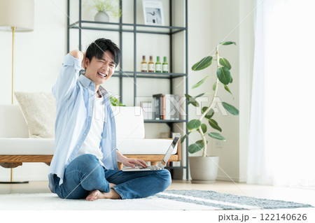 リビングでパソコンを使う若い男性 リビングでパソコンを使う若い男性 122140626