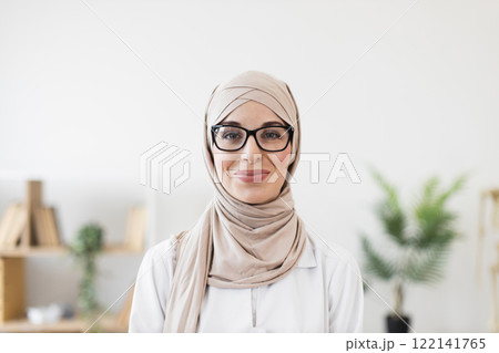 Portrait of a young Muslim woman doctor wearing hijab and glasses, exuding confidence and professionalism. Represents diversity, healthcare, and empowerment in medical field. Portrait of a young Muslim woman doctor wearing hijab and glasses, exuding confidence and professionalism. Represents diversity, healthcare, and empowerment in medical field. 122141765