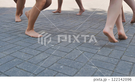 Ballet dancers stroll barefoot on a cobblestone street, savoring the end of the school year after a rehearsal Ballet dancers stroll barefoot on a cobblestone street, savoring the end of the school year after a rehearsal 122142096