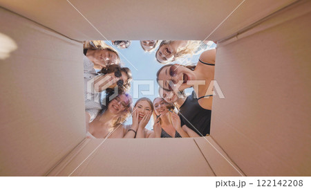 Excited high school girls express surprise and happiness while looking inside a cardboard box during their summer break 122142208
