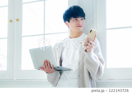 窓際でパソコン作業をする青年 122143726