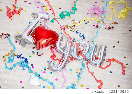 Confetti, streamers and foil balloon I Love You are lying on the floor. 122143926