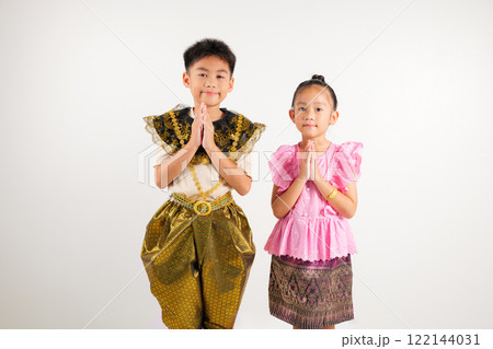 Portrait Thailand kid boy and girl smiling traditional Thai dress costume posing to pay respect in studio isolated white background, Happy primary and kindergarten children sawasdee symbol or welcome 122144031