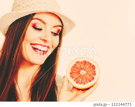 Woman holding half of grapefruit citrus fruit in hand 122144771