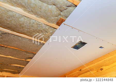 New drywall goes up on ceiling, over insulation during construction home 122144848