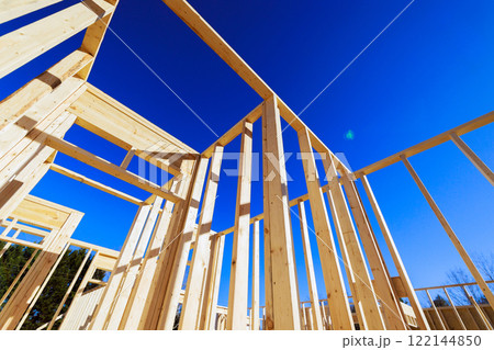 Workers are constructing wooden framework for building at sunlight overhead. 122144850