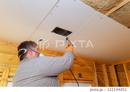 Contractor worker uses saw tool to install ventilation duct while renovating home interior. 122144852