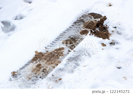 A single tire track marks the snowy landscape, covered with mud A single tire track marks the snowy landscape, covered with mud 122145272