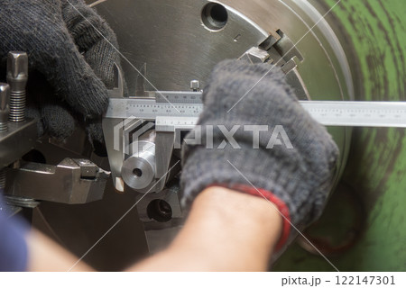 Close up scene the lath machine operator measuring dimension of turning parts by Vernier caliper. Close up scene the lath machine operator measuring dimension of turning parts by Vernier caliper. 122147301