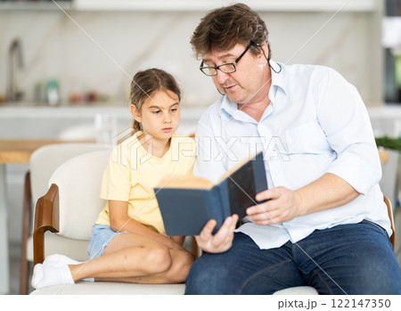 Father and daughter reading book together 122147350