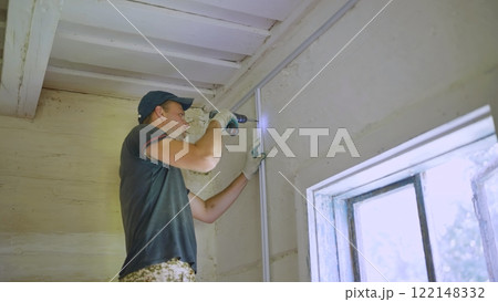An electrician works with a drill to create electrical wiring. An electrician works with a drill to create electrical wiring. 122148332