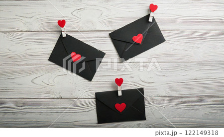 Black Envelopes with Red Heart Decorations on White Wooden Background 122149318