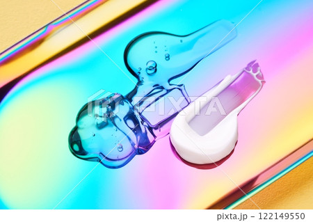 A drop of cosmetic serum, cream and gel on a multicolored background in shades of blue and lilac. A drop of cosmetic serum, cream and gel on a multicolored background in shades of blue and lilac. 122149550