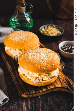 Salad burger with eggs, tomatoes, garlic and cheese on a board on a table vertical view Salad burger with eggs, tomatoes, garlic and cheese on a board on a table vertical view 122149602