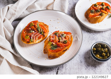 Italian crostini with sun-dried tomatoes, capers and spices on a plate on a table Italian crostini with sun-dried tomatoes, capers and spices on a plate on a table 122149627